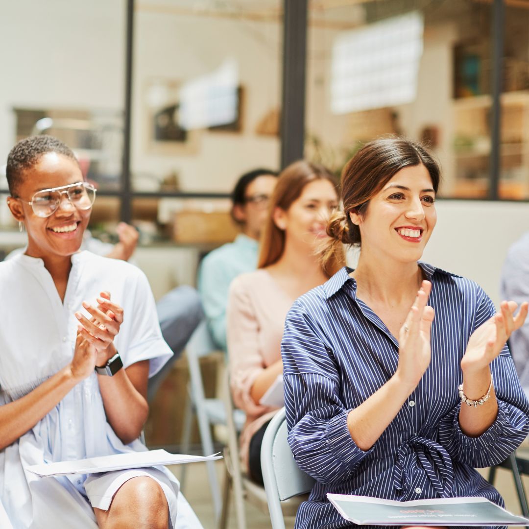 Audience members clapping and enjoying themselves at a leadership conference.