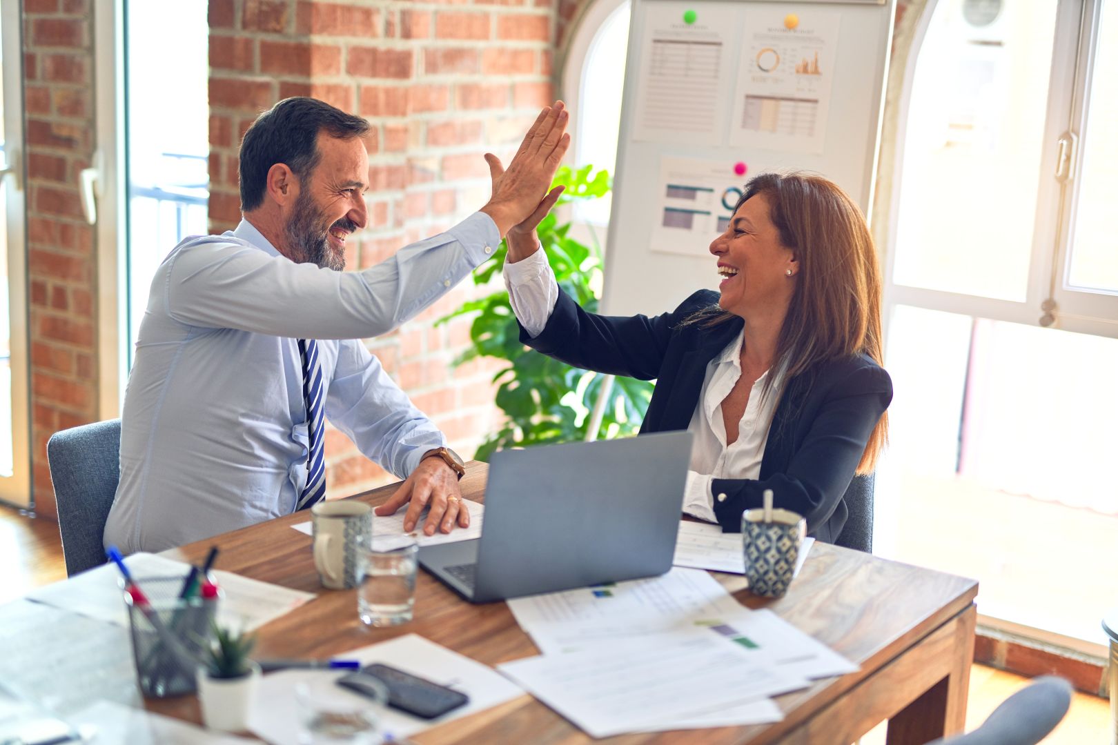 Man and woman leaders giving each other high five after signing up for emails from AMPED Leadership.