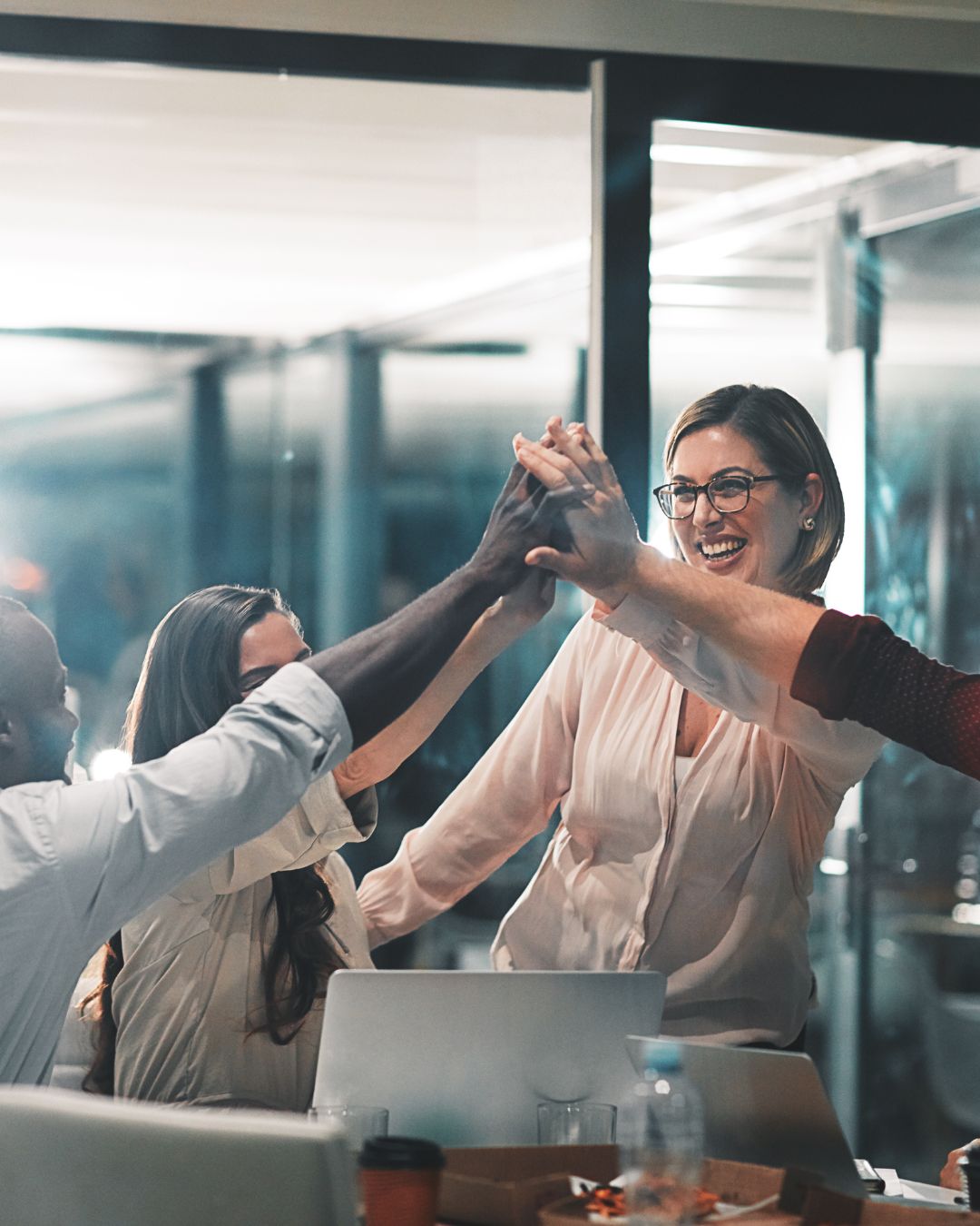 Group of team members in office giving each other high fives during leadership training with AMPED Leadership.