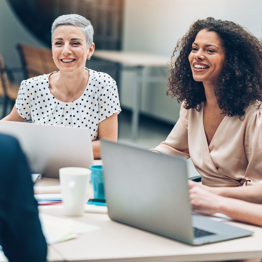 Women smiling and laughing during discussion at leadership workshop. 